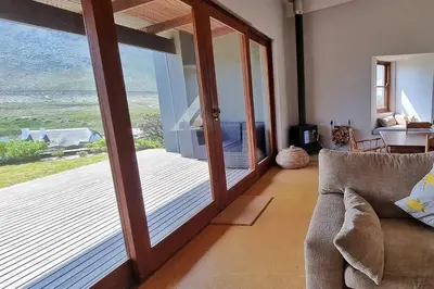 a living room with a sliding glass door to a patio at Hilltop Heaven, Walk to beach, Pool, Ocean & River views in Pringle Bay