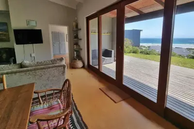 a living room with a view of the ocean at Hilltop Heaven, Walk to beach, Pool, Ocean & River views in Pringle Bay