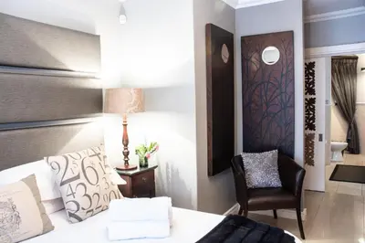 a hotel room with a bed and a chair at Avemore Jan Cats No 5 full backup power in Stellenbosch