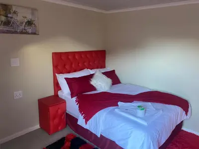 a bedroom with a large bed with a red headboard at SABATH LODGE in Cape Town