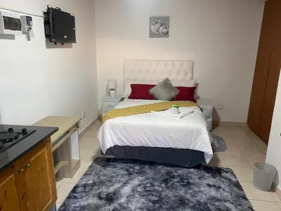 a small bedroom with a bed and a kitchen at SABATH LODGE in Cape Town
