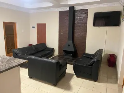 a living room with black leather furniture and a stove at SABATH LODGE in Cape Town