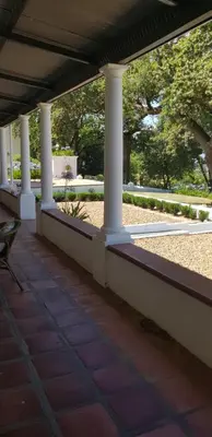 a porch with white columns and a bench on it at Diamant Estate in Paarl