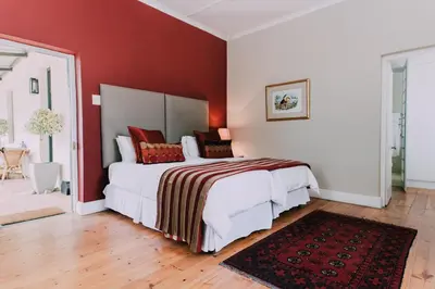 a bedroom with a large bed with red walls at Diamant Estate in Paarl