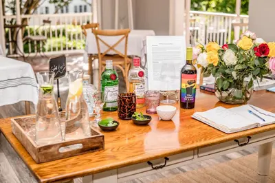a wooden table with bottles and glasses and flowers at Corner House Residence in Franschhoek