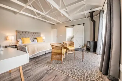 a bedroom with a bed and a table and chairs at Corner House Residence in Franschhoek