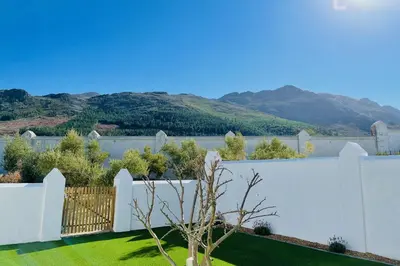 a white fence in a yard with mountains in the background at Droom Guesthouse in Franschhoek