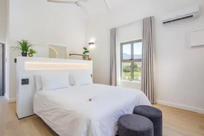 a white bedroom with a white bed and a window at Droom Guesthouse in Franschhoek