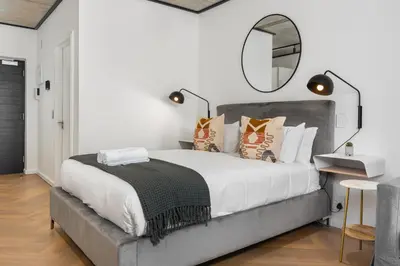 a bedroom with a large bed with a mirror on the wall at Bridgewater One Apartments in Cape Town
