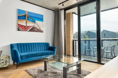 a living room with a blue couch and a glass table at Bridgewater One Apartments in Cape Town