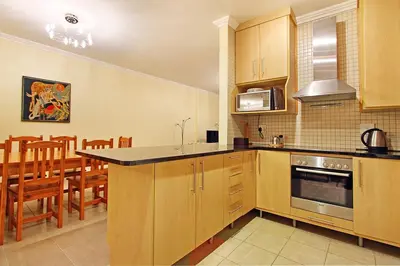 a kitchen with wooden cabinets and a dining room at Knightsbridge 407 by Host Agents in Cape Town