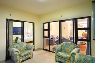 a living room with two chairs and a bedroom at Knightsbridge 407 by Host Agents in Cape Town