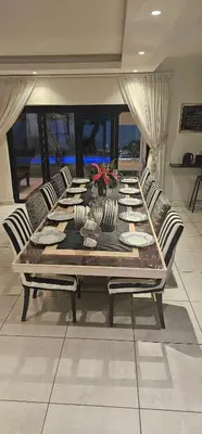a dining room table with chairs and a couch at Villa Parisienne Modern Guest house in Cape Town