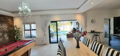 a dining room with a pool table and a dining room at Villa Parisienne Modern Guest house in Cape Town