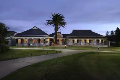 a house with a palm tree in front of it at 19th Hole Guest Lodge - Golfers paradise in Hermanus