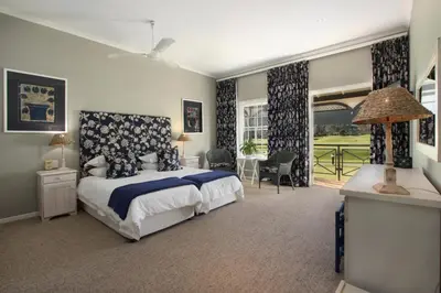 a bedroom with a bed and a large window at 19th Hole Guest Lodge - Golfers paradise in Hermanus