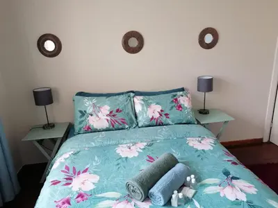 a bed with a blue comforter with two tables at Proleefic House on Florence in Bellville