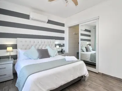 a bedroom with a large bed with a striped wall at Glennies Guesthouse in Somerset West