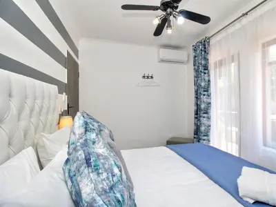 a bedroom with a white bed and a ceiling fan at Glennies Guesthouse in Somerset West