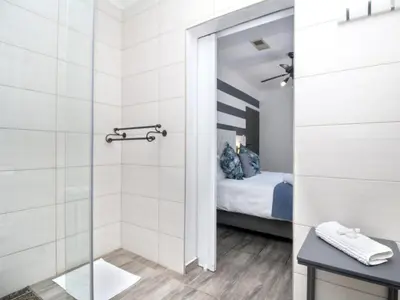 a bathroom with a shower and a bed at Glennies Guesthouse in Somerset West