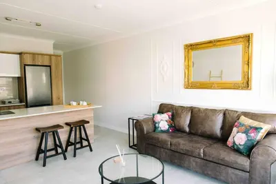 a living room with a couch and a counter at Bright and airy Parisian Gem close to the beach in Cape Town