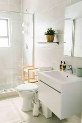 a white bathroom with a toilet and a sink at Bright and airy Parisian Gem close to the beach in Cape Town
