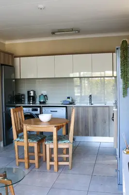 a kitchen with a wooden table and chairs at The Jade Somerset West in Cape Town