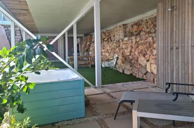 a bathroom with a tub and a stone wall at The Anchor, Luxury living for 2 with sea view and Jacuzzi in Gordonʼs Bay