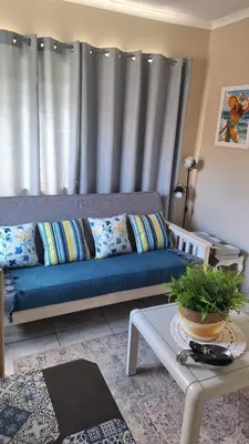a living room with a blue couch in front of a window at Senelle accomodation in Hermanus