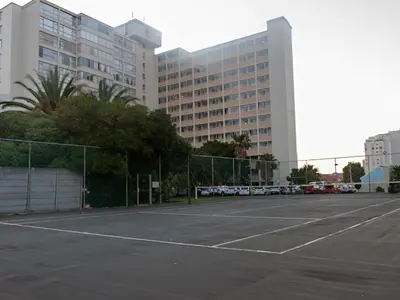 a parking lot with a tennis court in front of a building at Ocean-Song in Strand