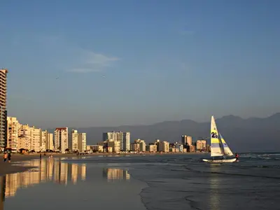 a sail boat on the beach with a city at Ocean-Song in Strand