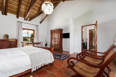 a bedroom with a bed and two rocking chairs at Aaldering Luxury Lodges in Stellenbosch