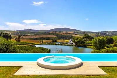 a hot tub on a wooden deck next to a river at Aaldering Luxury Lodges in Stellenbosch