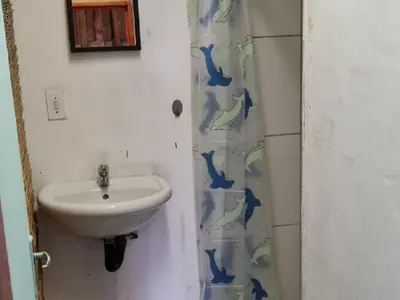 a bathroom with a sink and a shower curtain at Sunset beach backpackers in Bloubergstrand