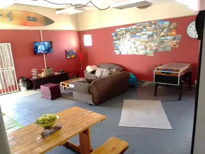 a living room with a couch and a table at Sunset beach backpackers in Bloubergstrand