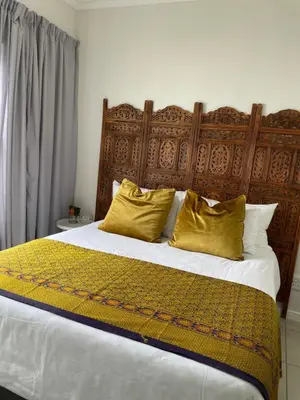 a bedroom with a large bed with yellow pillows at 417 The Sandown in Cape Town