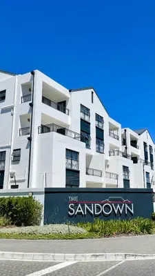 a white apartment building with a sign in front of it at 417 The Sandown in Cape Town
