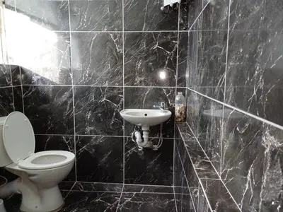 a black tiled bathroom with a toilet and a sink at Ojong's Court Bellville in Cape Town