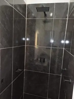 a shower with a black tiled wall at Ojong's Court Bellville in Cape Town