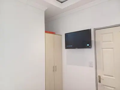 a bedroom with a flat screen tv on the wall at Ojong's Court Bellville in Cape Town
