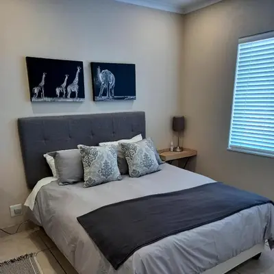 a bedroom with a bed with three pictures on the wall at Complete self-catering apartment close to the beach in Cape Town