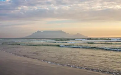 a view of the beach with a mountain in the background at Complete self-catering apartment close to the beach in Cape Town