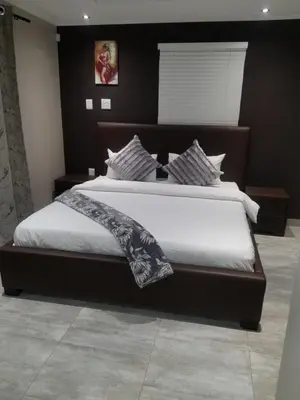 a bedroom with a large bed with white sheets at Prince Olive in Cape Town