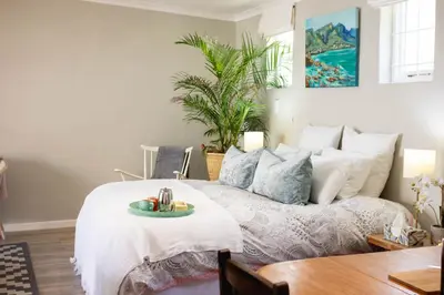 a bedroom with a bed with a tray of food on it at Goozi Garden Cottage in Hermanus