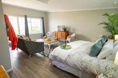 a bedroom with a bed and a living room at Goozi Garden Cottage in Hermanus