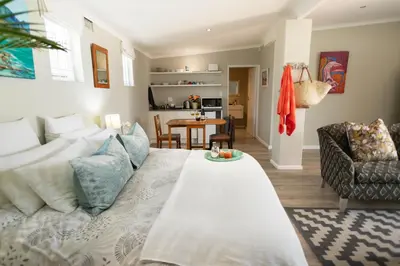 a living room with a white couch and a table at Goozi Garden Cottage in Hermanus