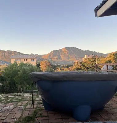 a blue tub sitting on a patio with mountains in the background at Edible Shores in Pringle Bay