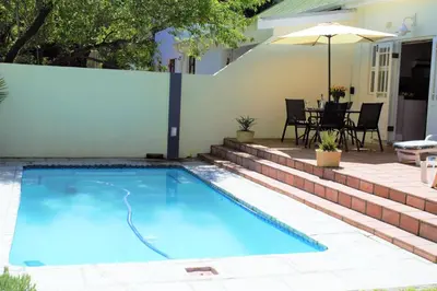 a swimming pool in a backyard with a table and an umbrella at Mafunyani Cottage in Franschhoek