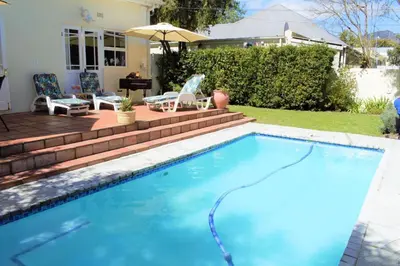 a swimming pool with a patio and a house at Mafunyani Cottage in Franschhoek