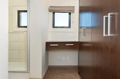 a bathroom with a wooden door and a window at The Manhattan Apartments in Cape Town